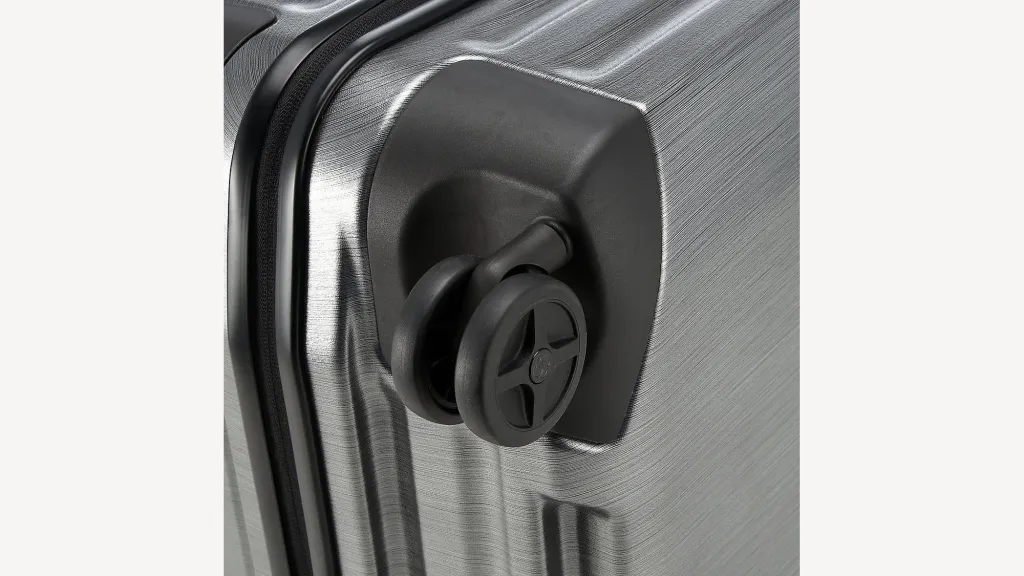 Detail of the wheel and ribbed corner of a Samsonite Inova suitcase.