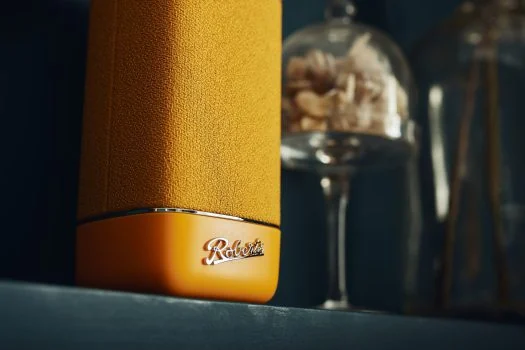 Detail van een gele Roberts Beacon-speaker met het Roberts-logo.