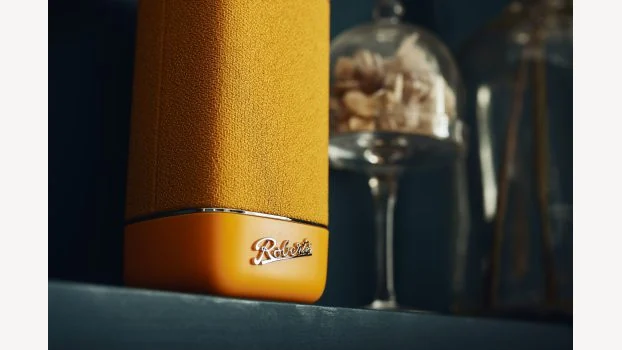 Detail van een gele Roberts Beacon-speaker met het Roberts-logo.