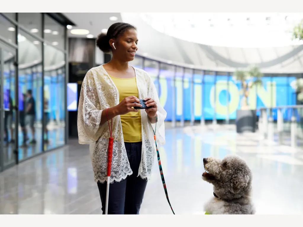 A user operates Hable One beside a guide dog at a railway station.