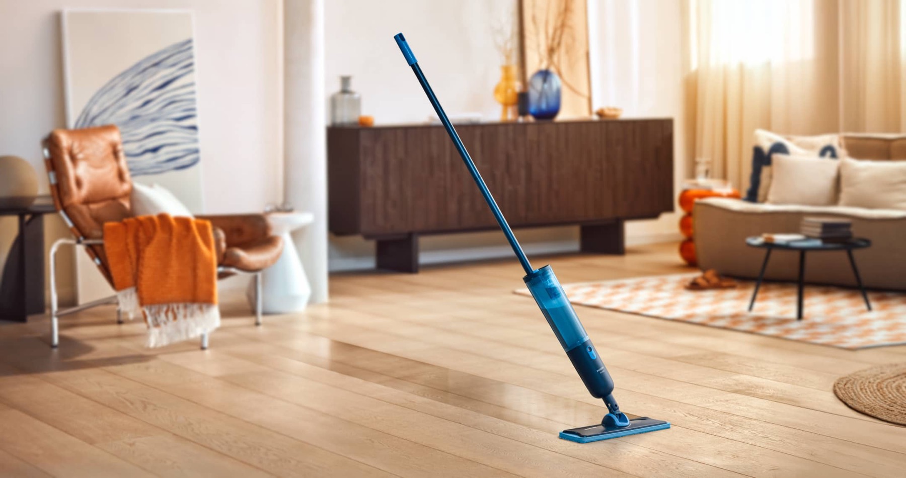 Philips OneUp met blauwe steel en reinigingskop in een woonkamer.