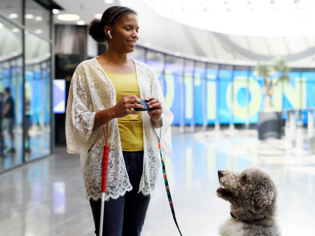 Een gebruiker bedient Hable One naast een geleidehond op een station.