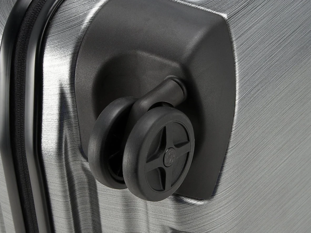 Detail des Rads und der gerippten Ecke eines Samsonite Inova‑Koffers.
